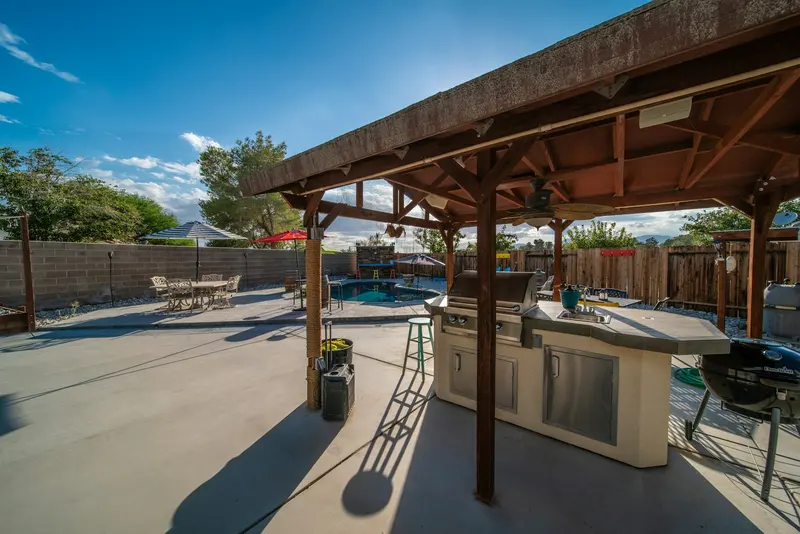 Área gourmet coberta com churrasqueira, bancada e vista para a piscina